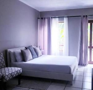 a white bedroom with a bed and a window at Samtip Sunset in Johannesburg