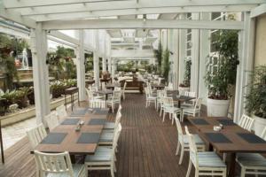 un restaurante con mesas de madera y sillas blancas en IL Campanario - Suíte, en Florianópolis