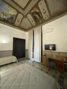 a room with a bed and a desk and a television at Resort CostantiNapoli 27 in Naples