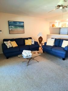 a living room with two blue couches and a table at Sunset Beach Condo #54455 in Holmes Beach