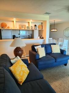 a living room with two blue couches and a kitchen at Sunset Beach Condo #54455 in Holmes Beach