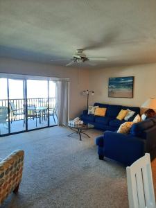 a living room with a blue couch and a balcony at Sunset Beach Condo #54455 in Holmes Beach