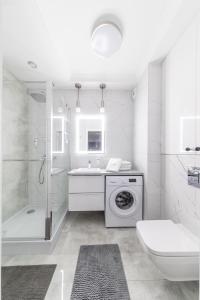 a white bathroom with a washing machine and a sink at ResiNest Apartamenty Kopernik in Białystok