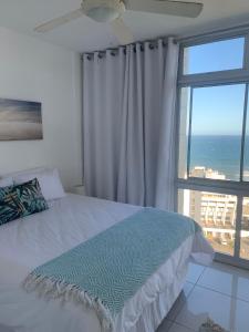 a bedroom with a bed and a large window at Aziel by the Sea in Ballito
