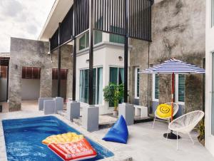 Nadda Pool Villa Ranong في Ban Bang Rin (1): مسبح مع طاولة وكراسي ومظلة