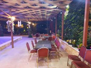 un patio con mesa, sillas y piscina en Green House, en Zūbiyā