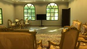 Habitación con sillas, mesa y ventanas. en Big Guest House - استراحة كبيرة en Al Ḩamīdīyah