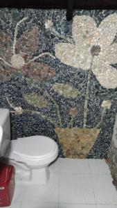 a bathroom with a toilet and a mosaic wall at La chonta in Capurganá