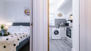 a bedroom with a bed and a kitchen with a washing machine at Stylish Modern Apartment in Conwy in Conwy