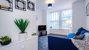 a living room with a blue couch and a tv at Stylish Modern Apartment in Conwy in Conwy