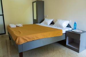 a bedroom with a large bed with yellow sheets and a table at Anandvan Beach Resort in Alibaug