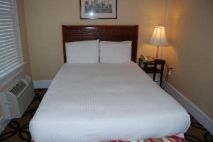 ワシントンにあるWindsor Inn Hotelのベッドルーム(白いベッド、ランプ、電話付)