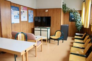 a waiting room with tables and chairs and a tv at AUBERGE DE JEUNESSE in Colmar