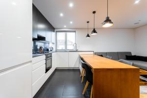 a kitchen with white cabinets and a wooden table at Luxury Apartment in the City Centre in Košice