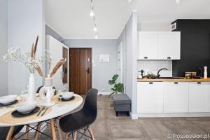 a kitchen with a table and chairs and a kitchen with white cabinets at Kameralny apartament nad morzem Possession pl in Gdańsk