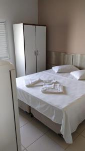 a bed with white sheets and utensils on it at Hotel Pousada Miami in Itanhaém