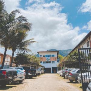 a street with cars parked in front of a building at Chalés Sununga Flats a 1 minuto da praia in Ubatuba