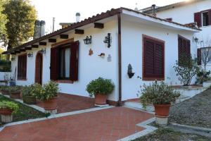 a white house with brown shutters and potted plants at Appartamento Boscodisotto in Rapolano Terme