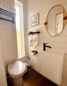 a white bathroom with a toilet and a mirror at Entirely Private Tiny Home - 1 Mile to UF in Gainesville