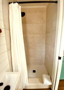 baño con ducha con cortina blanca en Entirely Private Tiny Home - 1 Mile to UF en Gainesville