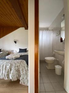 1 dormitorio con cama, aseo y lavamanos en Hostería Suiza - Ex Casita Suiza en San Carlos de Bariloche