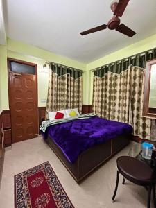 a bedroom with a purple bed and a ceiling fan at YATIKA HOMESTAY in Shimla