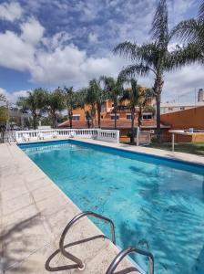 una piscina en un complejo con palmeras en Saint Tropez hotel en Villa Carlos Paz
