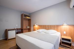 1 dormitorio con 1 cama grande y pared de madera en Hotel Italia, en Balneário Camboriú