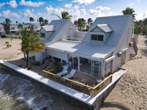 an aerial view of a house on the beach at La Plage Bleue feet in the water with swimming pool in Baie Nettle