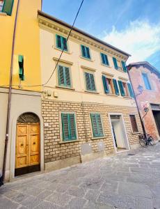 a yellow building with green shutters and a wooden door at relais L’Imperatore in Prato