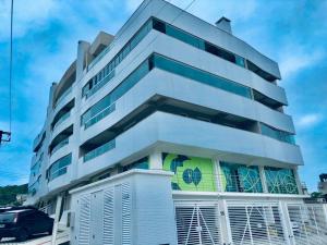 Aluguel Bombinhas - Temporada - Até 7 pessoas في بومبينهاس: مبنى أبيض فيه سيارة متوقفة أمامه