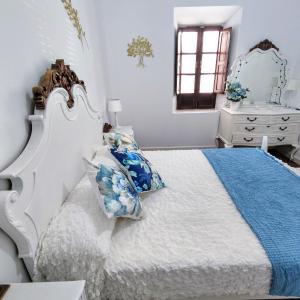 een slaapkamer met een wit bed met blauwe kussens bij Munigua House in Villanueva del Río y Minas