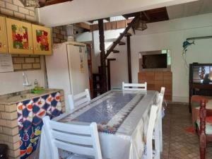 a kitchen with a table with chairs and a refrigerator at Chalé Canez 1 in Farol de Santa Marta