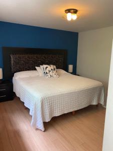 1 dormitorio con cama blanca y pared azul en Sinaloa 46, en Ciudad de México