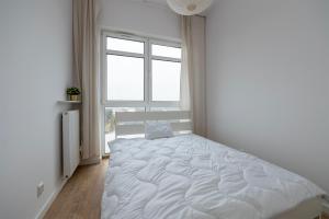 a white bedroom with a large bed with a window at Penthouse with a View of Lodz & Free Parking in Łódź