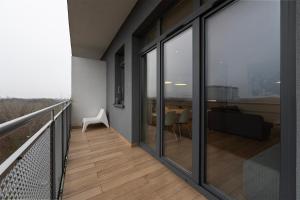 een balkon met glazen schuifdeuren en een tafel bij Penthouse with a View of Lodz & Free Parking in Łódź