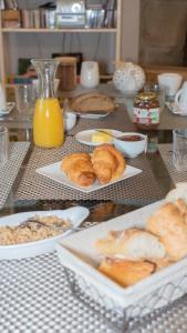 - une table recouverte de assiettes de viennoiseries et de jus d'orange dans l'établissement Domaine de la Basse Orme, à Les Iffs