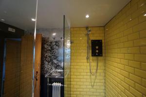 a bathroom with a shower with yellow brick walls at Birdcage Heritage Cottage - city centre vibrant Brighton in Brighton & Hove