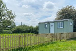 a green tiny house behind a fence at Shepherd Hut in Warwick
