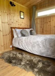 a bedroom with a bed and a window and a rug at Shepherd Hut in Warwick