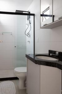 La salle de bains est pourvue de toilettes, d'un lavabo et d'un miroir. dans l'établissement Apartamento com a cara de Maceió, à Maceió