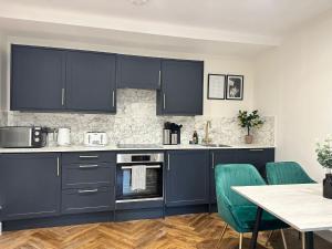 una cocina con armarios azules y una mesa con sillas verdes en Kingsize Bed Luxury Hideaway Retreat by the Sea, en Brighton & Hove