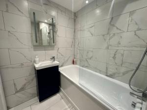 Baño blanco con bañera y lavamanos en Kingsize Bed Luxury Hideaway Retreat by the Sea, en Brighton & Hove