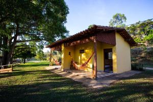 una pequeña casa amarilla con una hamaca en un parque en Garça Branca en São Roque de Minas