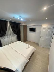 een slaapkamer met een groot wit bed en een televisie bij Double D Apartments in Lupeni