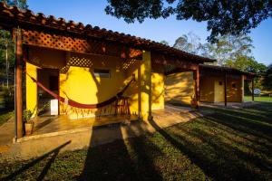 ein gelbes Haus mit einer Veranda und einem Hof in der Unterkunft Garça Branca in São Roque de Minas