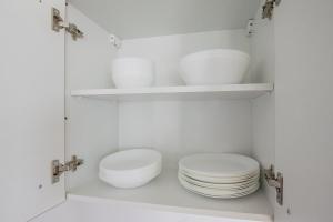 two white plates and bowls in a white cabinet at Tolstov House - 5 Room House with Terrace - 35 Min to Messe DUS in Mönchengladbach +24 photos