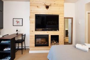 a bedroom with a fireplace with a tv above it at Impeccable Glacier Lodge Hotel Room w Pool+Hot Tub in Whistler