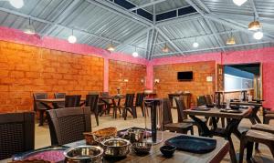 a restaurant with wooden tables and chairs and a pink wall at Treebo Trend Blooms & Berries Agro Tourism in Mahabaleshwar