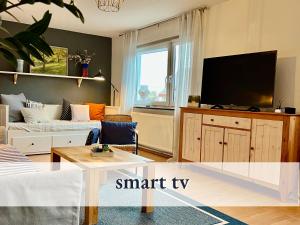 ein Wohnzimmer mit einem Flachbild-TV und einem Sofa in der Unterkunft Komfortables bestens ausgestattetes Appartement Nähe Karlsruhe & KIT in Linkenheim-Hochstetten